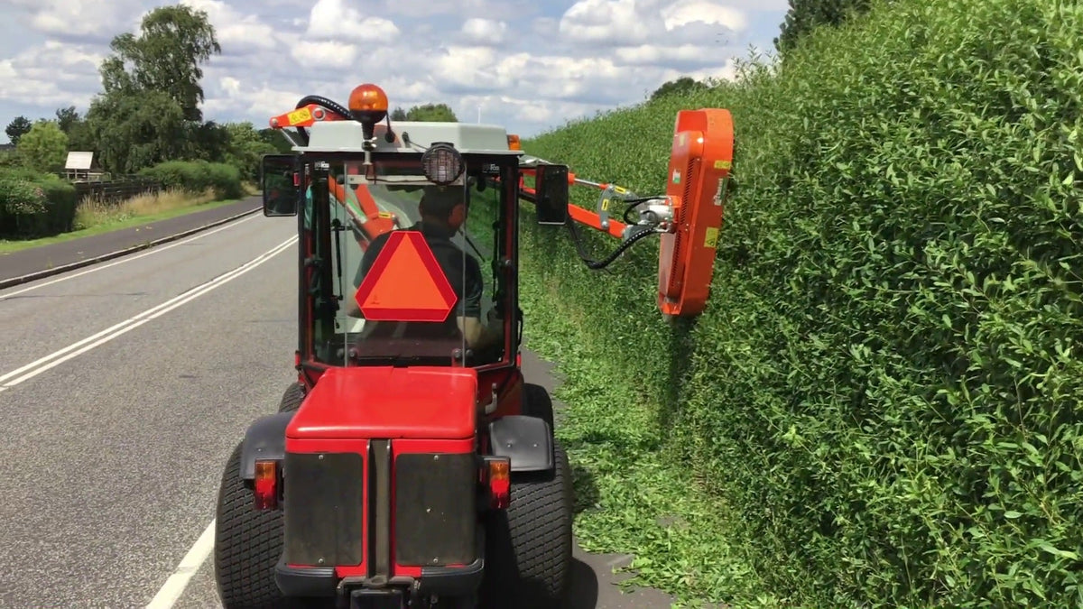 Rinieri BRM-C hydraulische heggenschaar op een rode tractor snoeit een haag langs de weg