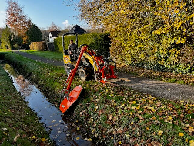 Rinieri maaiarm maait een slootkant vanaf een kniklader