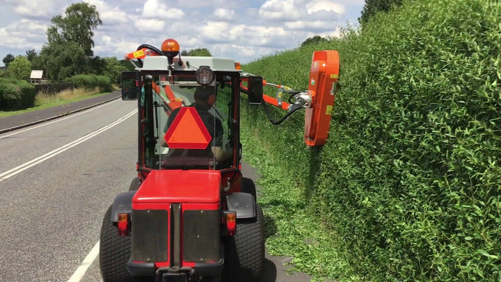 Rinieri BRM-C hydraulische heggenschaar op een rode tractor snoeit een haag langs de weg