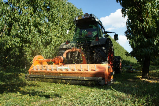 Rinieri versnipperaar aan een smalspoortractor in het grasrijpad tussen de fruitbomen