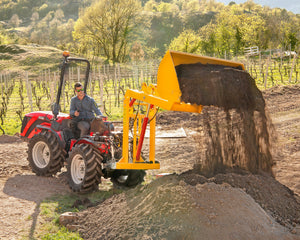 Rode tractor met Ilmer achterlader stort grond uit de transportbak in de wijngaard