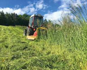 Rode tractor met Ilmer LMG heavy-duty strokenmaaier maait hoog gras