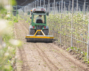Smalspoortractor met Ilmer PW 170 egalisatiewals op het rijpad onder hagelnetten