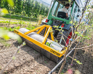 Ilmer PW 170 egalisatiewals walst de rijsporen vlak achter een smalspoortractor in de boomgaard