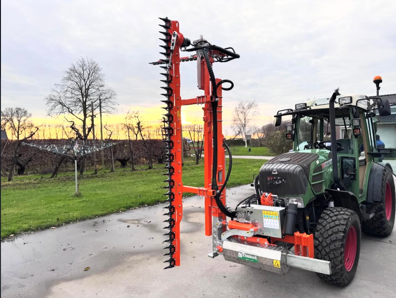 Fendt smalspoortractor met Rinieri heggenschaar bij zonsondergang in de boomgaard